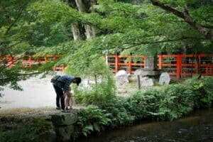 A serene moment between father and child in a Kyoto park by the river.